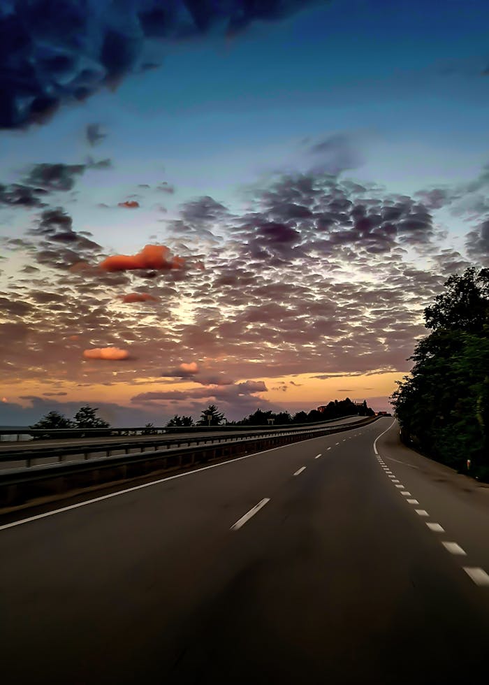 about-02 Serene highway scene with a stunning sunset sky, perfect for travel themes.